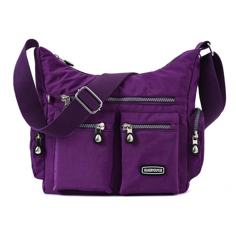 Purple shoulder bag with multiple pockets and a visible brand logo on a white background