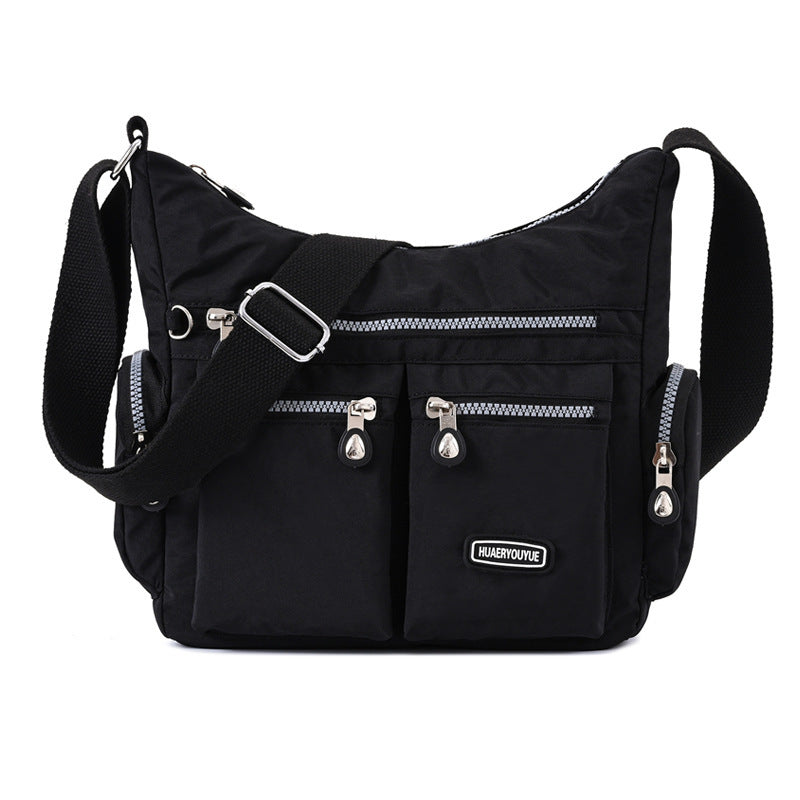 Black shoulder bag with silver zippers on a white background