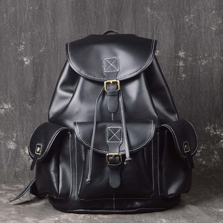 Black leather backpack with gold buckles on a textured gray background