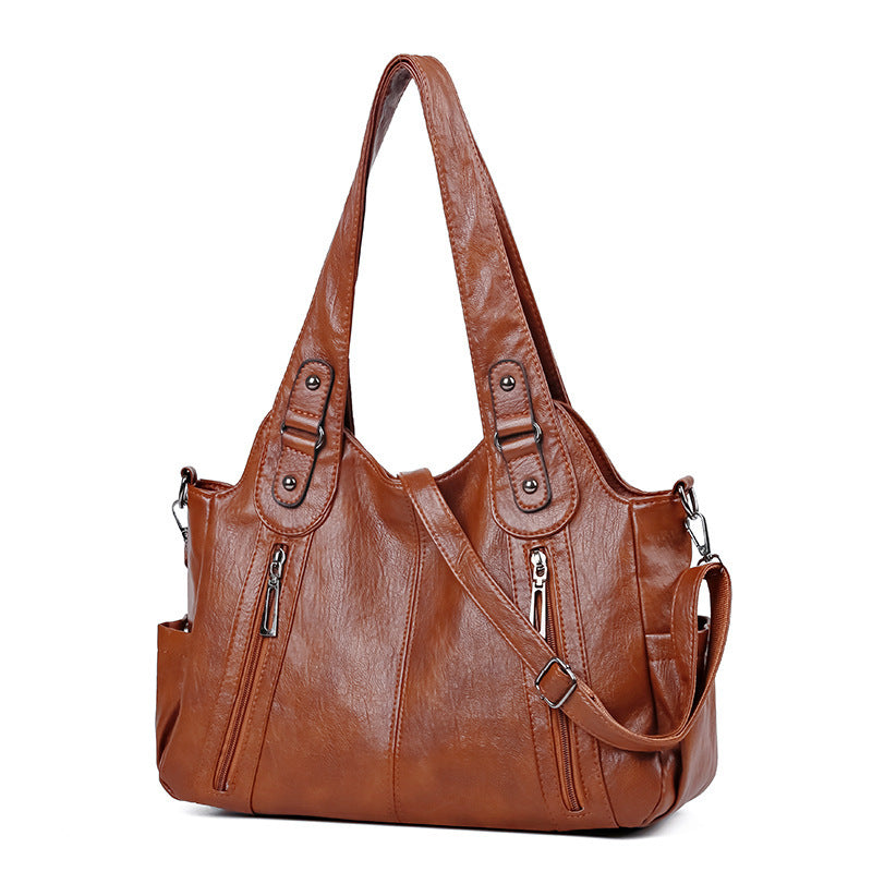 Brown leather handbag with shoulder strap on a white background