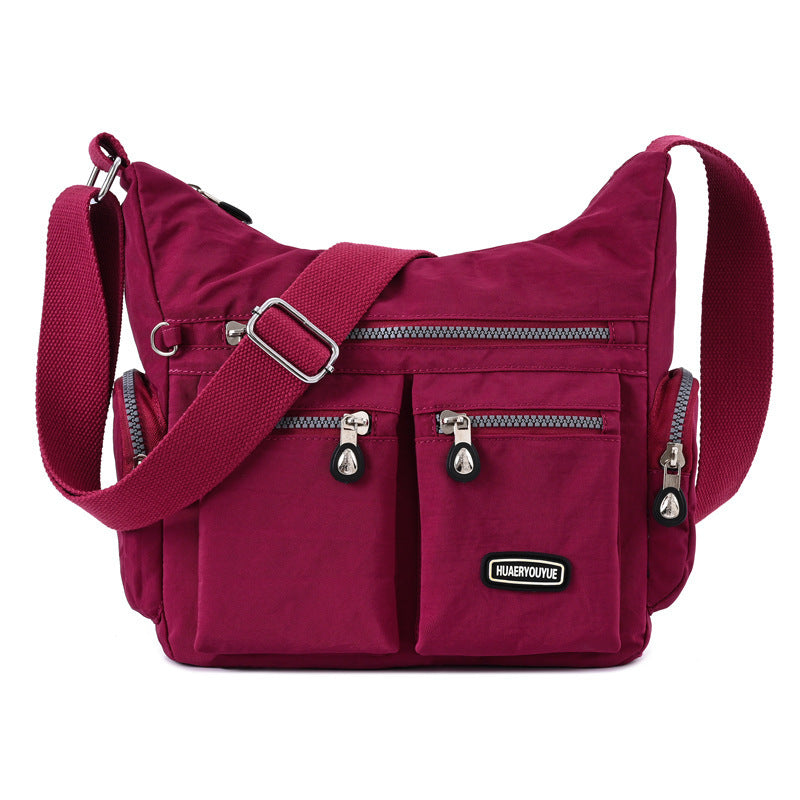 Red shoulder bag with multiple zippers on a white background