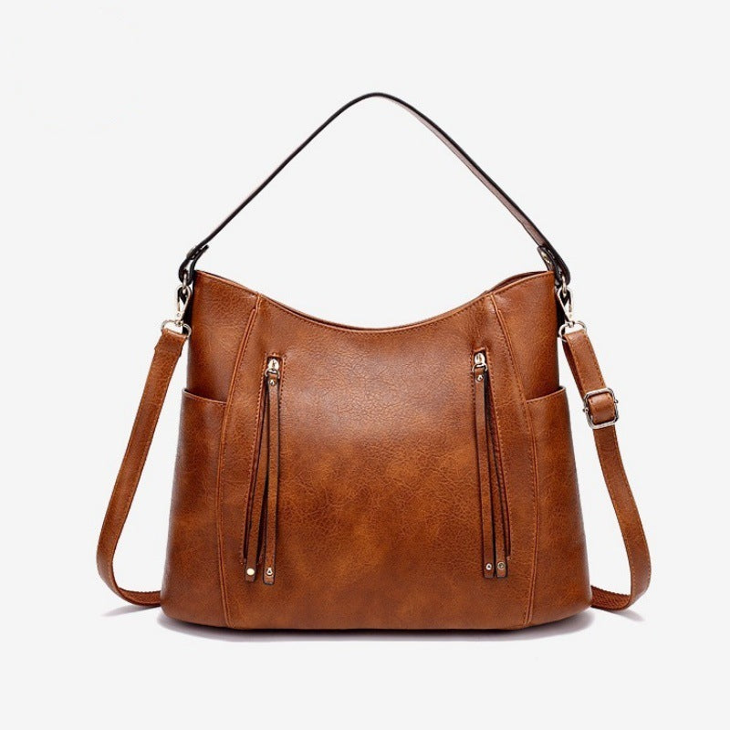Brown leather handbag with shoulder strap on a white background