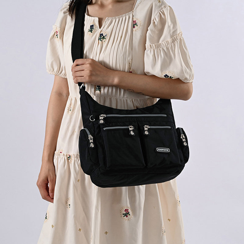 Person wearing a black crossbody bag against a light background