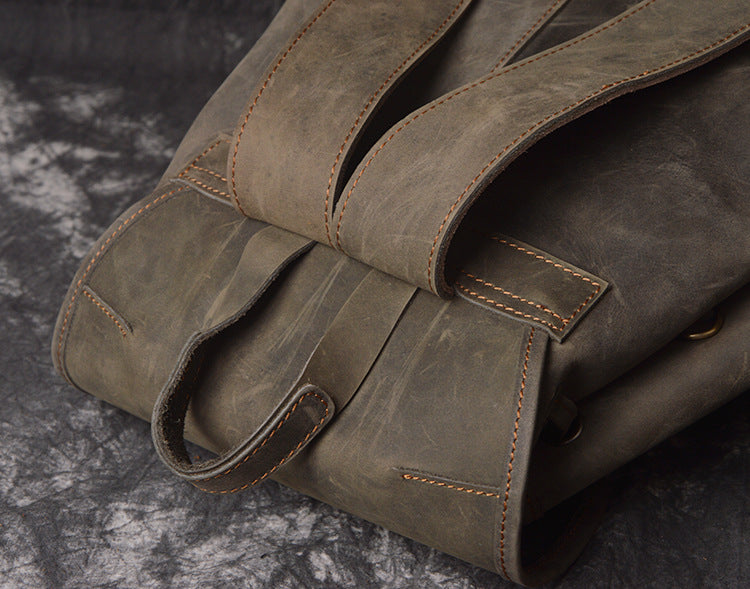 Close-up of a brown leather bag with visible stitching on a dark textured background