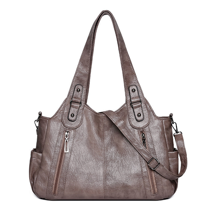 Brown leather handbag with multiple pockets and zippers on a white background