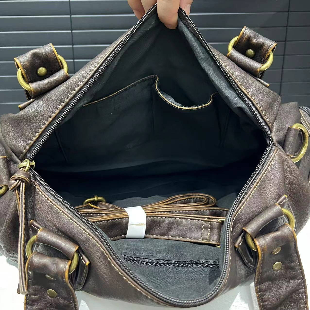 Brown leather bag with gold accents held open, showing its interior.