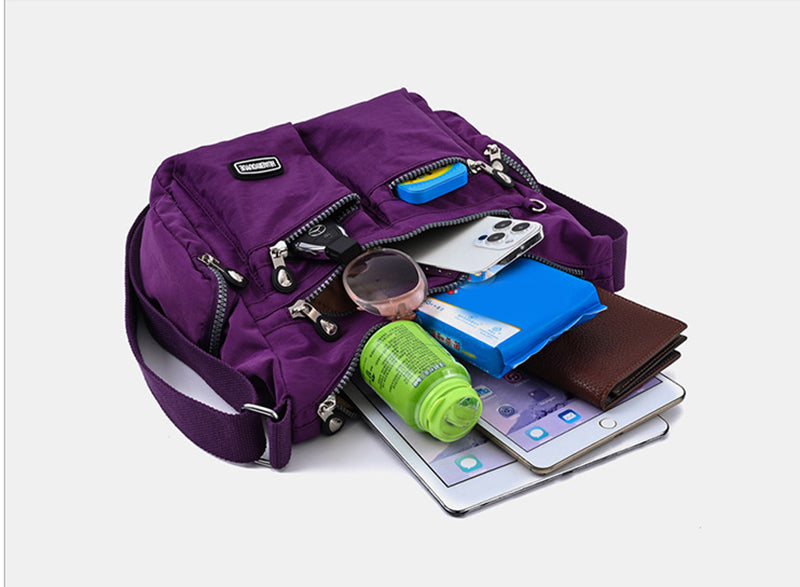 Purple backpack with various items including a phone, bottle, and tablet on a white background