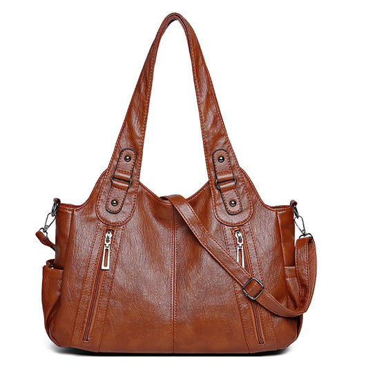 Brown leather handbag with multiple pockets and straps on a white background