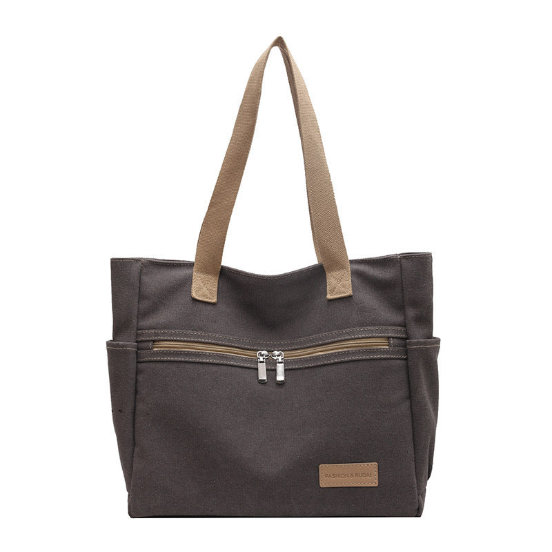 Gray tote bag with brown handles and zipper on a white background