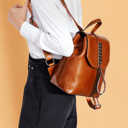 Brown leather backpack worn by a person on an orange background
