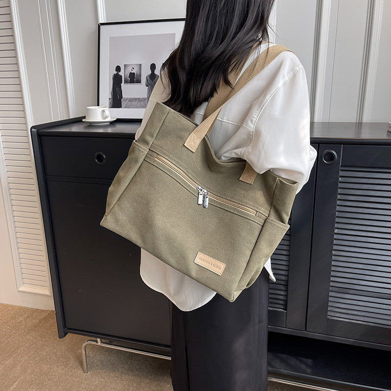 Person holding a green tote bag in an indoor setting