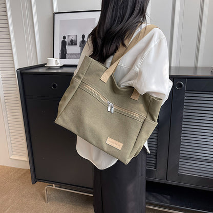 Person holding a green tote bag in an indoor setting