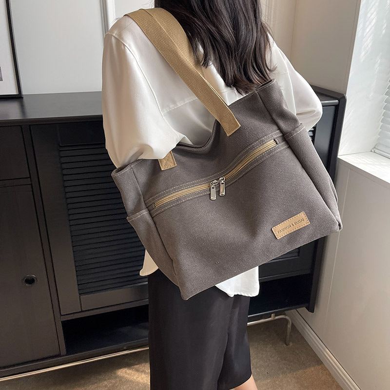 Person wearing a gray backpack with a beige strap indoors.