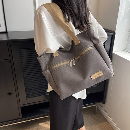 Person wearing a gray backpack with a beige strap indoors.
