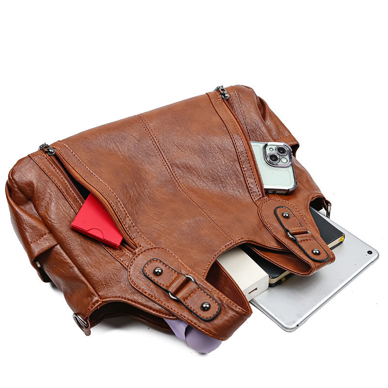 Brown leather bag with a phone and tablet inside on a white background