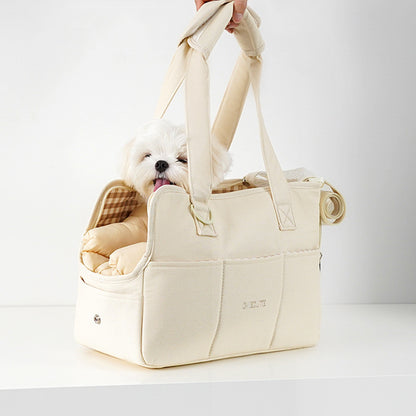 White dog in a beige pet carrier with a checkered pillow on a white background