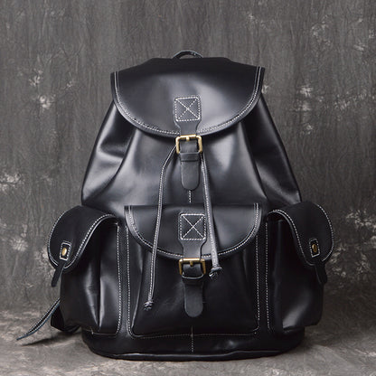Black leather backpack with gold buckles on a textured gray background