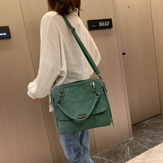 Person wearing a white shirt and blue jeans with a green handbag in front of a door with a number 8610.