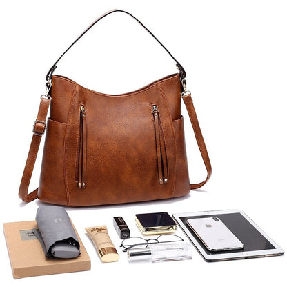 Brown leather handbag with various items on a white background
