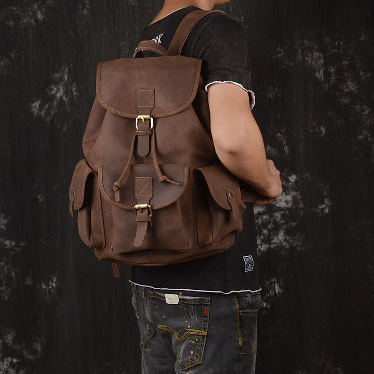 Person wearing a brown leather backpack against a dark background