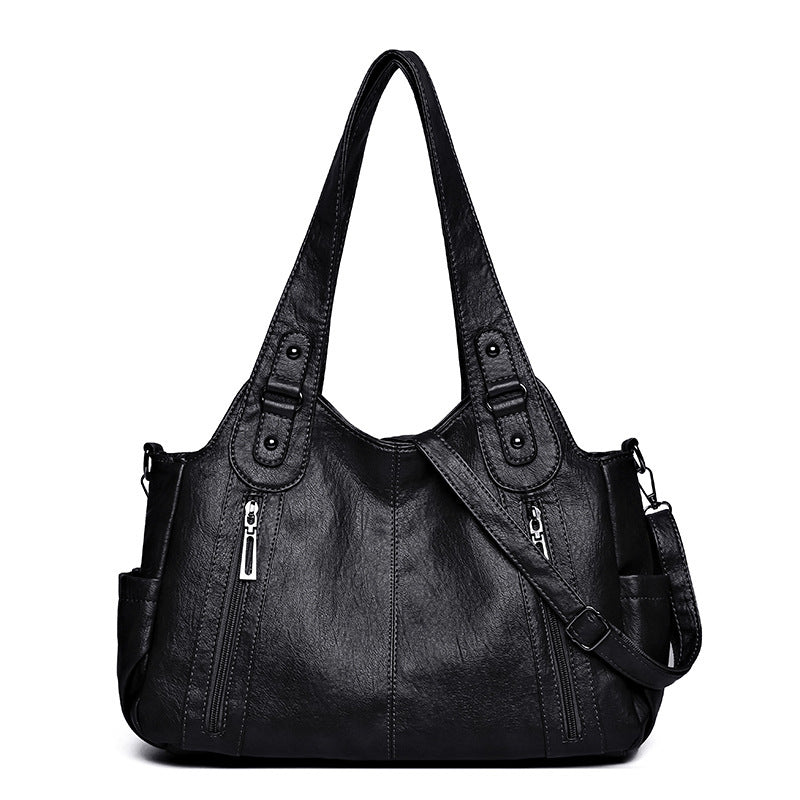Black handbag with multiple pockets and zippers on a white background