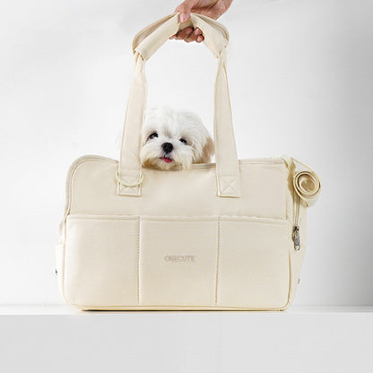 Small white dog peeking out from a beige pet carrier with 'Oriole' branding on a light gray background.