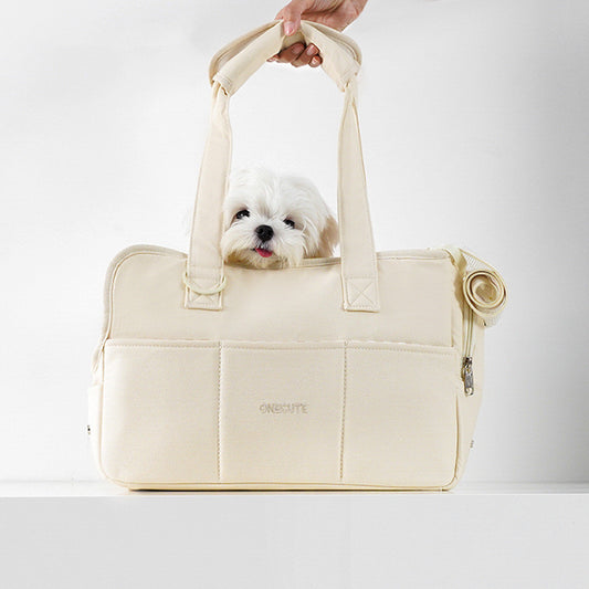 Small white dog peeking out from a beige pet carrier with 'Oriole' branding on a light gray background.