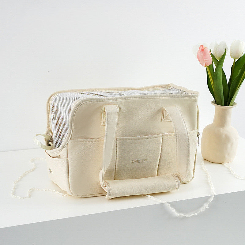 Beige toiletry bag on a white surface with a vase of tulips in the background