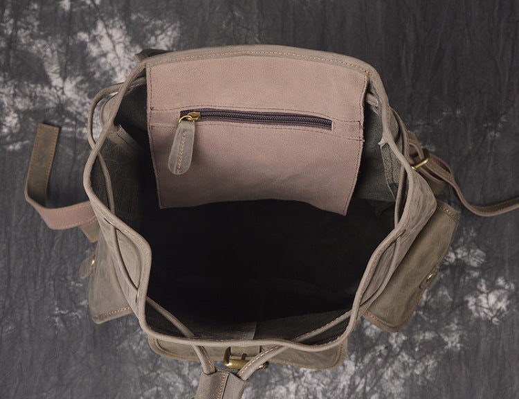 Gray backpack with a zipper pocket on a textured gray background