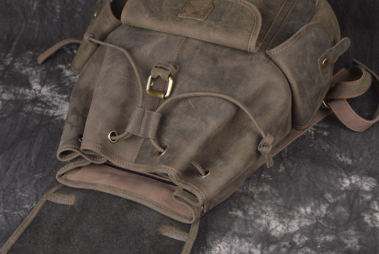 Brown leather backpack on a dark textured surface