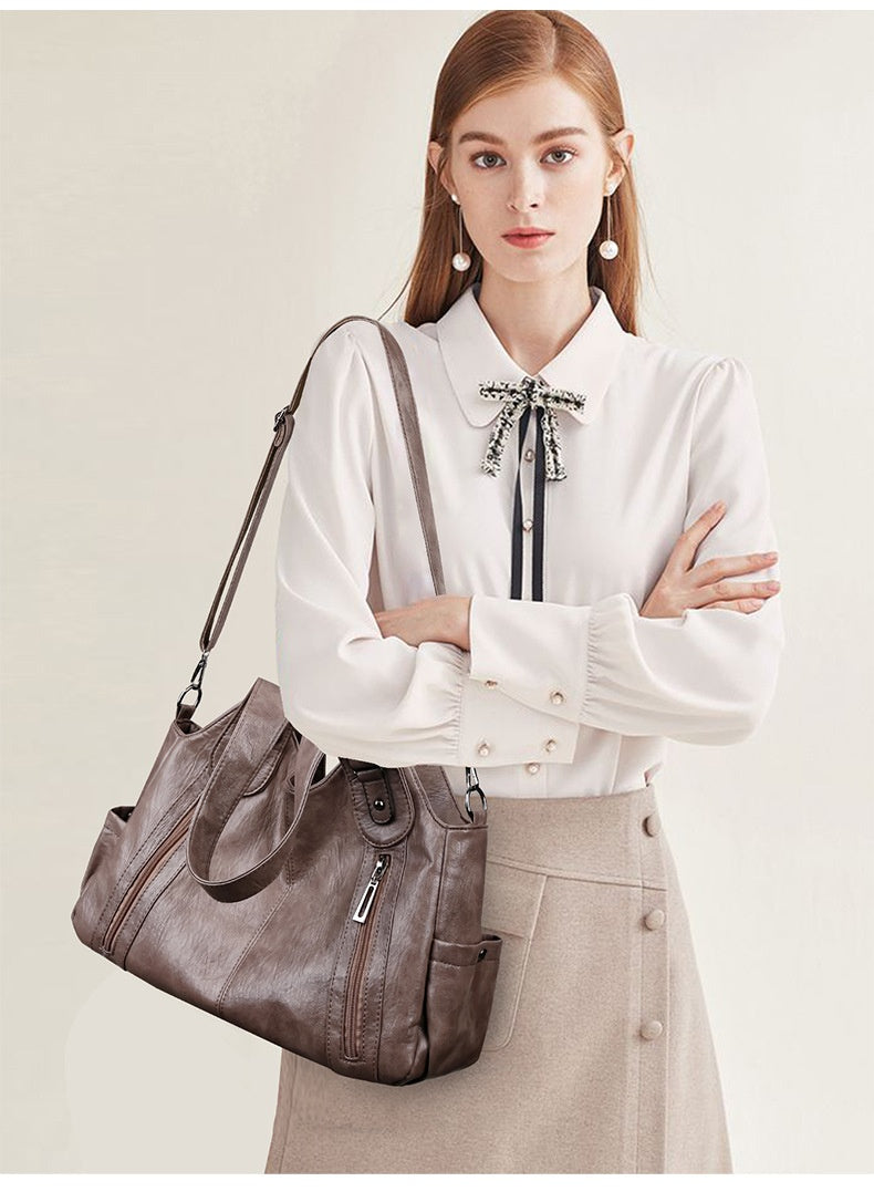 Woman holding a gray handbag against a plain background