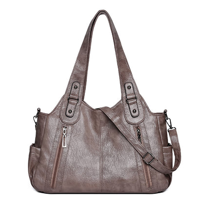 Brown leather handbag with multiple pockets and zippers on a white background